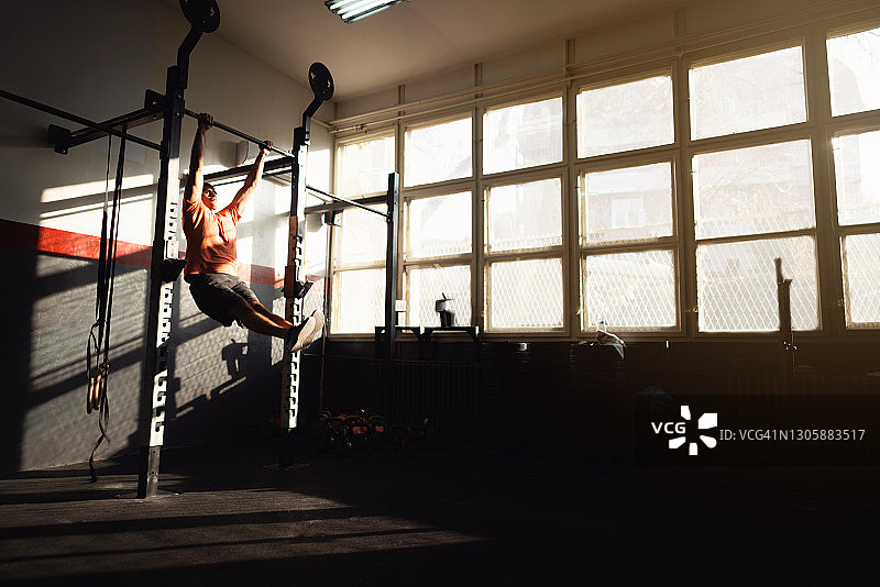一个健康的年轻人在健身房里做蝴蝶引体向上图片素材