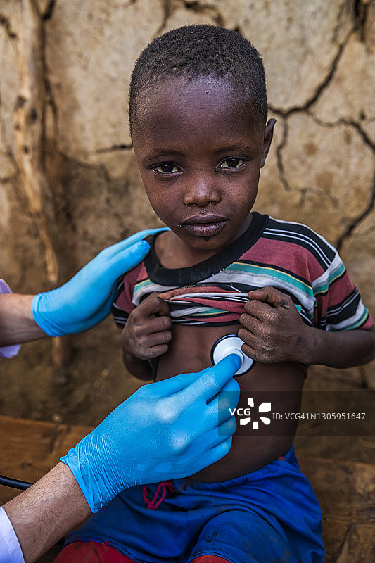 在肯尼亚的一个小村庄，医生正在检查一个年轻的非洲男孩图片素材
