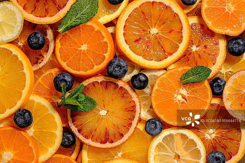俯视图的食物背景与红色和黄色的桔子片，橘子，蓝莓和柠檬。从上面图片素材