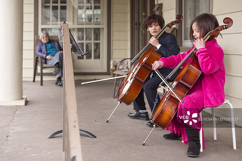 孩子们在前廊为年迈的邻居演奏大提琴图片素材