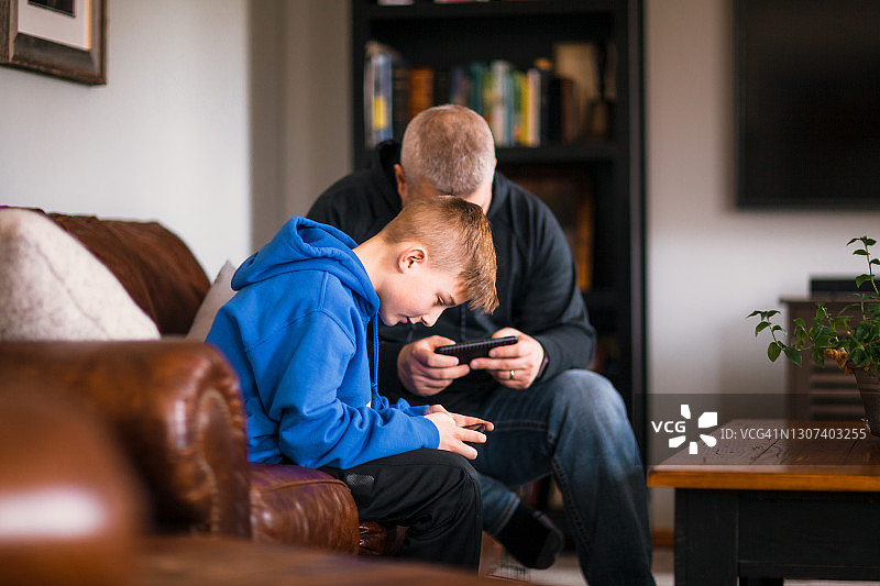 父亲和儿子在用手机玩电子游戏图片素材