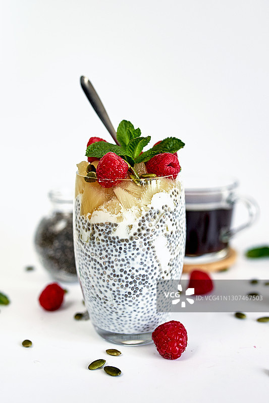 在白色的背景上，用草莓，覆盆子，菠萝，蓝莓和南瓜子做成的一个罐子图片素材