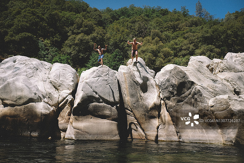 两个男孩从尤巴河的巨石上跳下来图片素材