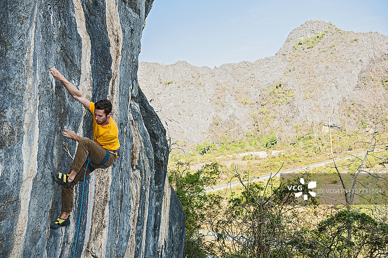 在老挝，一名男子爬上石灰岩悬崖图片素材