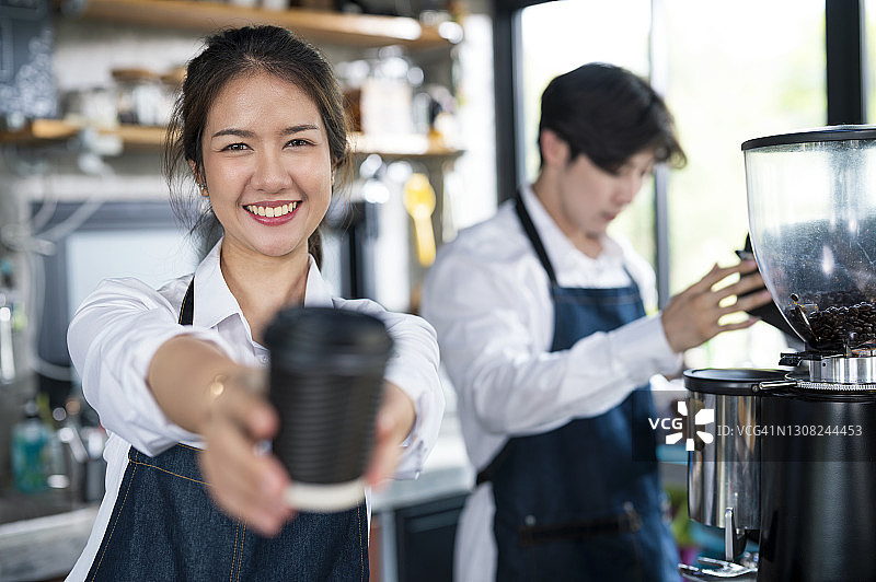 图为咖啡店老板在柜台上为顾客端上一杯咖啡。小企业主，服务意识和客户服务。图片素材