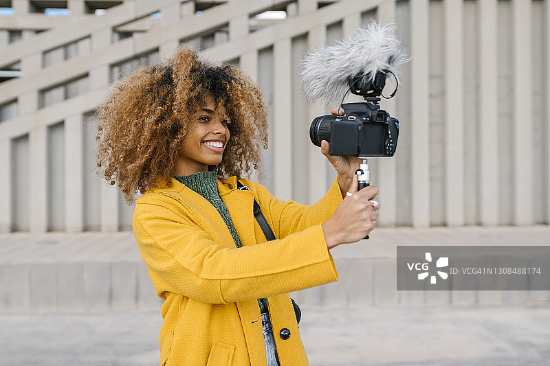 一个微笑的非洲女人在人行道上通过摄像头拍视频时，目光移开图片素材