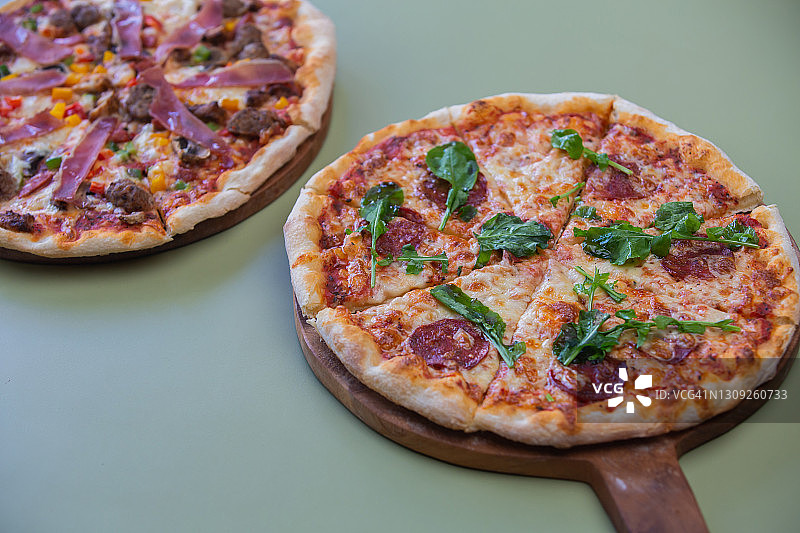 两种不同的美味新鲜的披萨在桌子上的特写图片素材