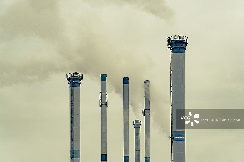 高大的工厂烟囱在天空中冒烟图片素材