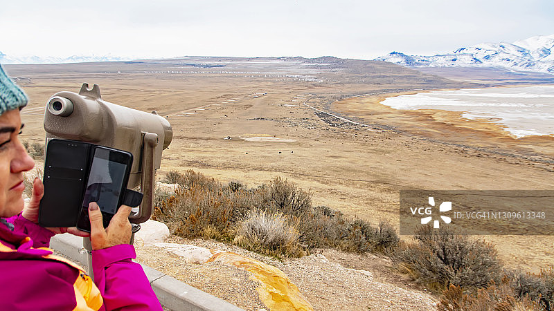 妇女通过望远镜观察羚羊岛的景观-大盐湖，犹他州图片素材