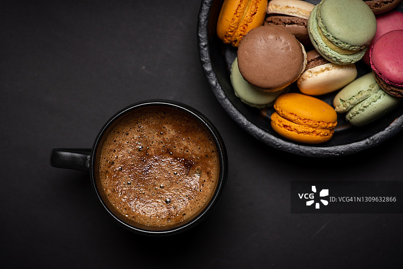 马卡龙、五颜六色的甜点和一杯在深色背景上的咖啡图片素材