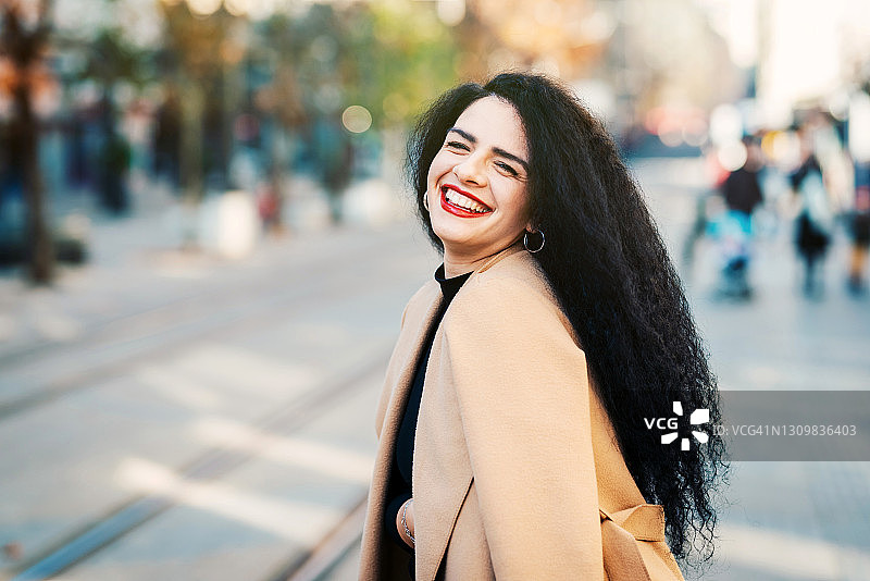 一个美丽微笑的年轻白人女人的画像在街上。城市/城市街道照片。图片素材