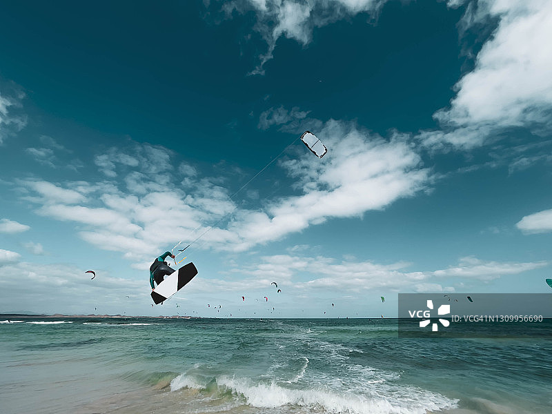 西班牙多风的富埃特文图拉岛，一大群人在玩风筝滑板。图片素材