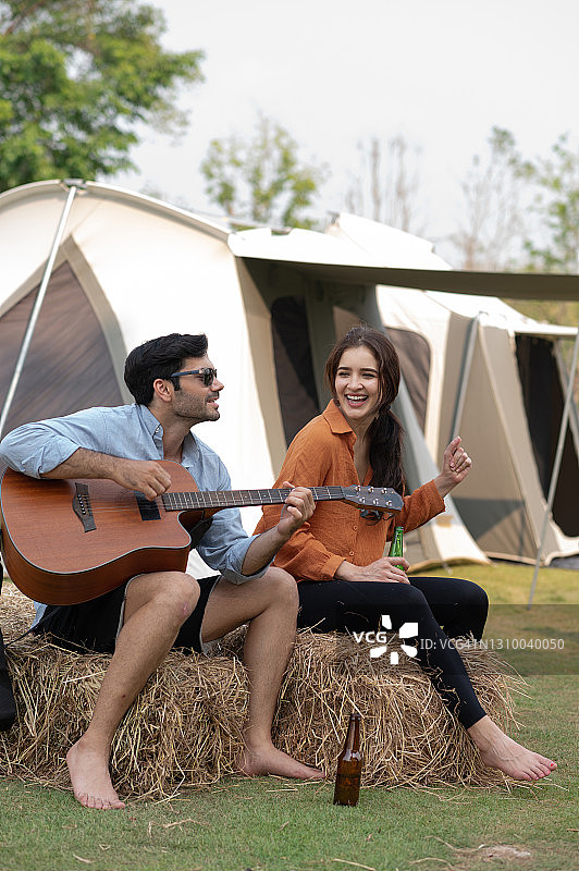 一对年轻的情侣喜欢在露营地弹吉他图片素材