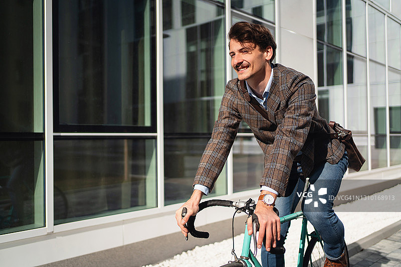 微笑着骑自行车的现代男人图片素材
