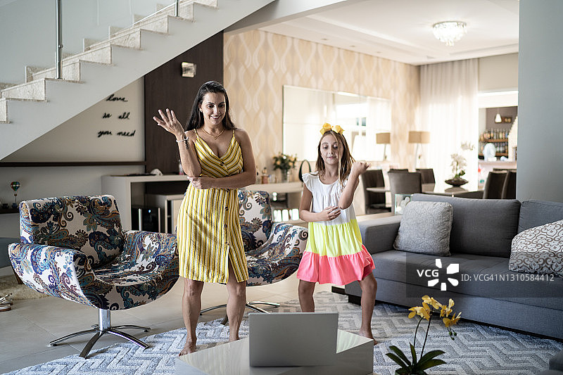 妈妈和女儿在家里的笔记本电脑前跳舞图片素材