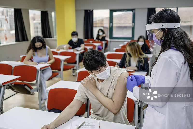 冠状病毒大流行期间，护士在学校为学生接种疫苗图片素材