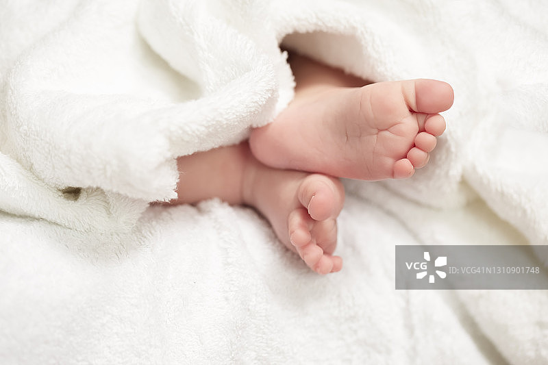 婴儿和新生儿概念。近距离拍摄一个四周大男婴的脚在白色毛巾。水平的形象定位图片素材