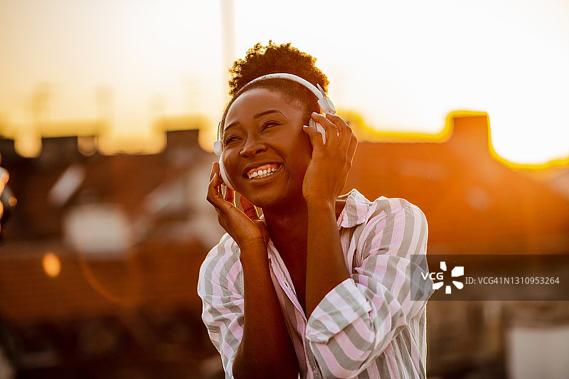 年轻的非洲裔美国妇女享受在屋顶上听音乐图片素材