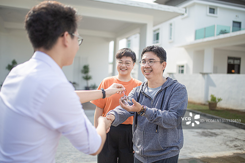 亚洲华人家庭搬进新房子，从房地产经纪人那里得到了房子钥匙图片素材