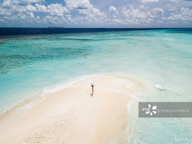 年轻的成年女子在马尔代夫的沙滩上奔跑，对抗着碧绿的海水图片素材