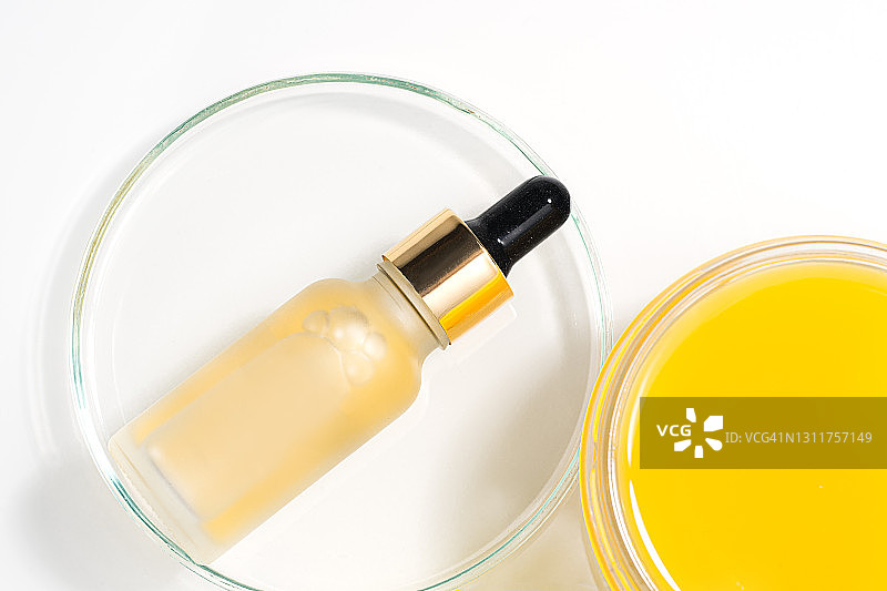 用皮氏培养皿滴管和橙汁配制化妆品瓶中维生素C血清的美容概念。图片素材