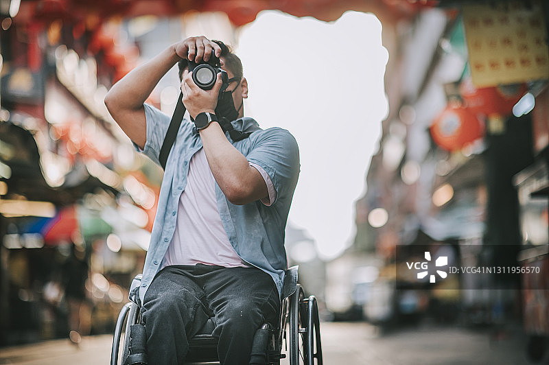 亚洲华人男性残疾人坐在轮椅上拍摄中国城图片素材