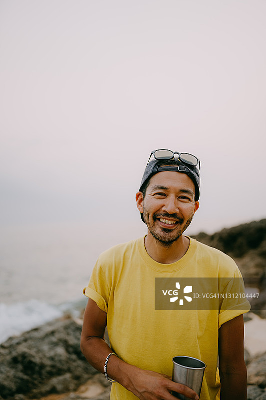 黄昏时分，一名日本男子在海滩上对着照相机大笑图片素材
