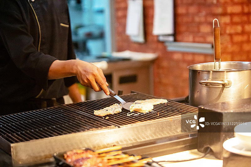 厨师把肉放在烤架上烤图片素材