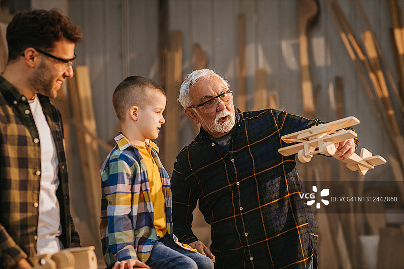 一家三代人在木工作坊里玩木制玩具图片素材
