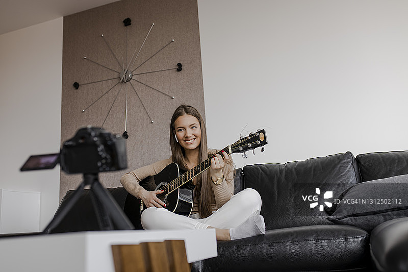 年轻美丽的女性是在她的家里，弹吉他图片素材
