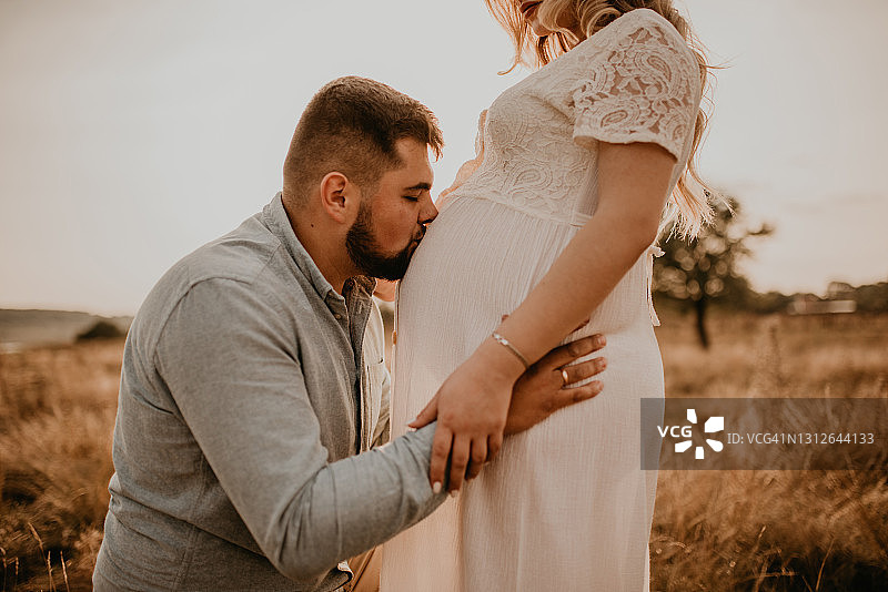 丈夫抱着怀孕的妻子，手放在大肚子上亲吻肚子图片素材