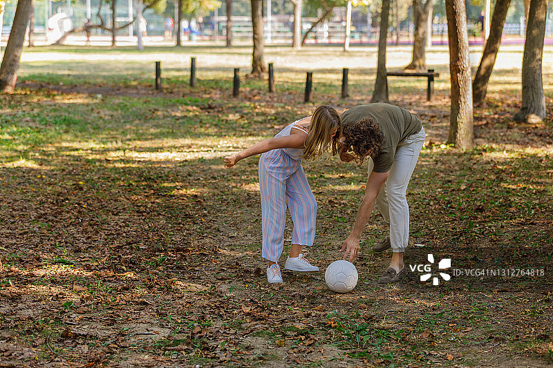快乐的爸爸和女儿在享受大自然，踢足球。图片素材