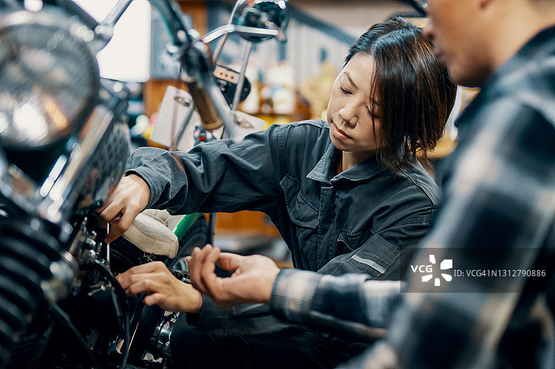中年女性修车师在修车店学习摩托车修理图片素材