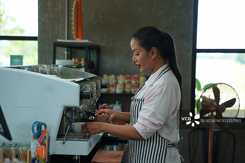 一名女服务员在咖啡店准备一杯咖啡的肖像。图片素材