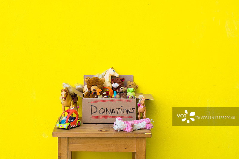 黄色背景上有儿童玩具的捐赠纸箱图片素材