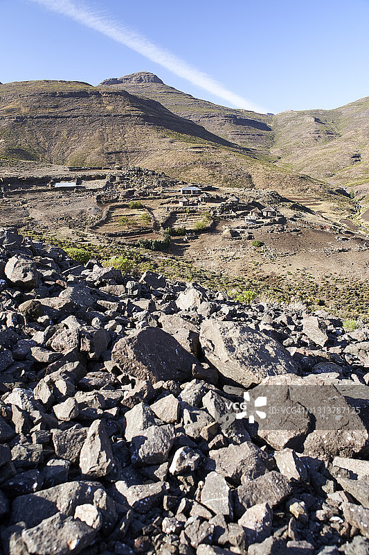 一个偏远的小村庄的垂直视图，定居在一个岩石山谷下山莱索托图片素材