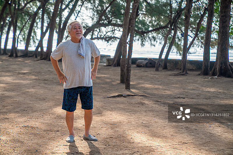 快乐的亚洲老人早上在海滩上锻炼。图片素材