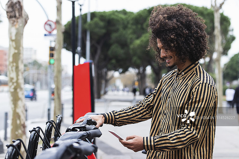 微笑的男人在自行车停车场用手机图片素材