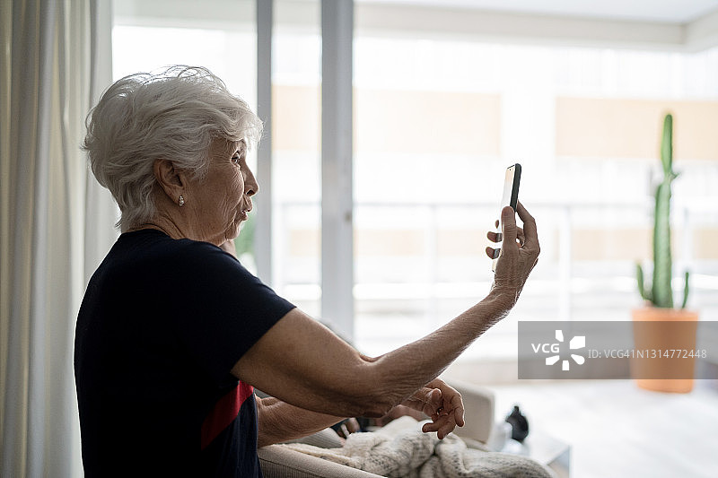 一位在家里用智能手机进行视频通话的资深女士图片素材