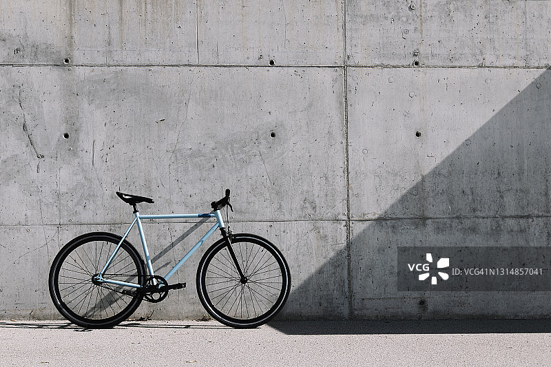 一辆自行车斜靠在户外街道上的灰色混凝土墙上。图片素材