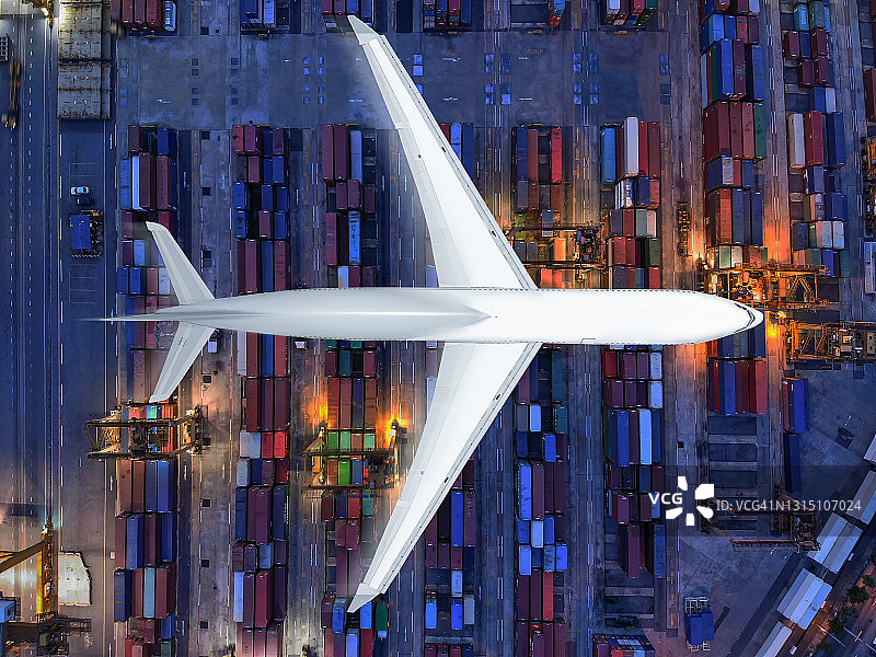 鸟瞰图/在港口上空将集装箱装上货轮运往目的地的飞机。图片素材
