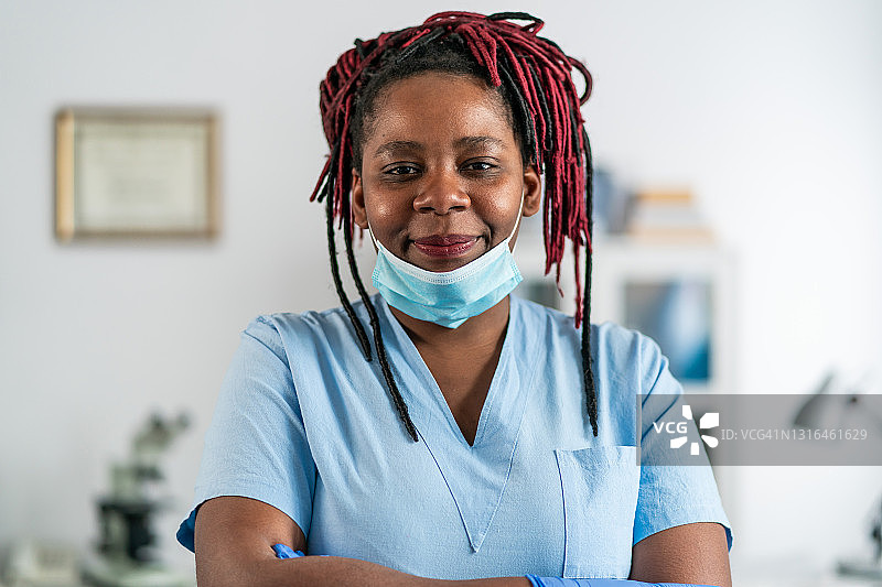 冠状病毒疫情期间，中年非洲裔女医生双臂交叉站在医生的办公室里图片素材