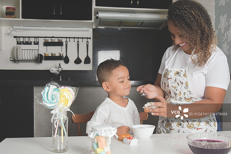 母亲和儿子在厨房玩纸杯蛋糕和糖衣图片素材