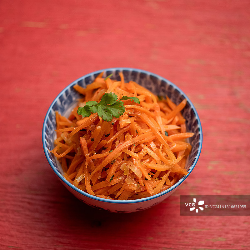辣胡萝卜，传统的东方沙拉。健康的有机素食零食。顶视图的碗上的红色背景。泛亚洲美食图片素材