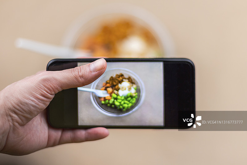 一个人的特写照片的健康午餐在一个塑料容器在棕色的背景。图片素材