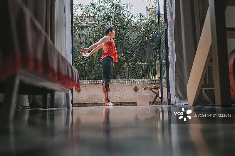 亚洲华人中年妇女瑜伽调解在家放松锻炼，周末休闲时间在后院图片素材