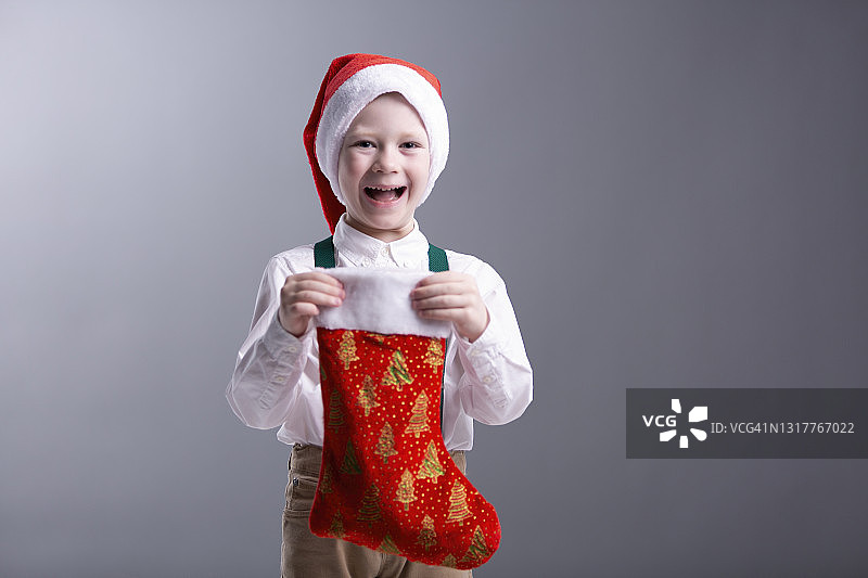美丽可爱的男孩站着，微笑着，拿着圣诞礼物图片素材