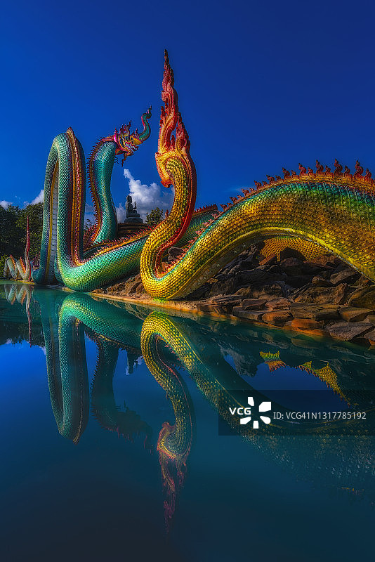 泰国乌汶拉察他尼帕普邦寺那迦蛇像与水和清澈的天空的倒影图片素材