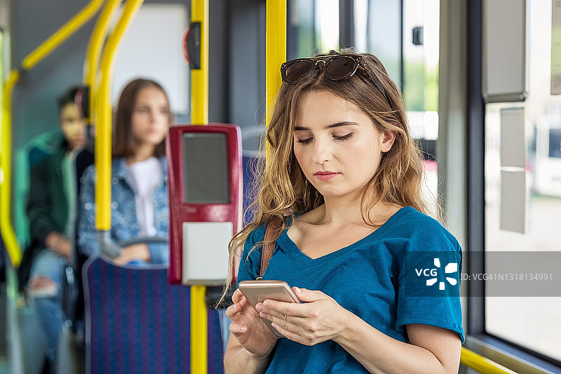 年轻女子在公共交通工具上使用智能手机图片素材
