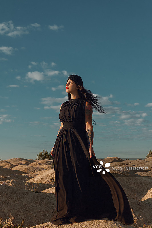 在沙漠中穿着黑色裙子和头巾的女人近距离图片素材